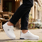 Lifestyle shot of bugatti Franc white leather sneakers, with perforated details, worn with dark jeans.
