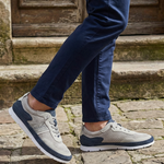 Lifestyle close-up of Bugatti Clipperton sand comfort low top sneakers with dark blue chinos on a stone surface.
