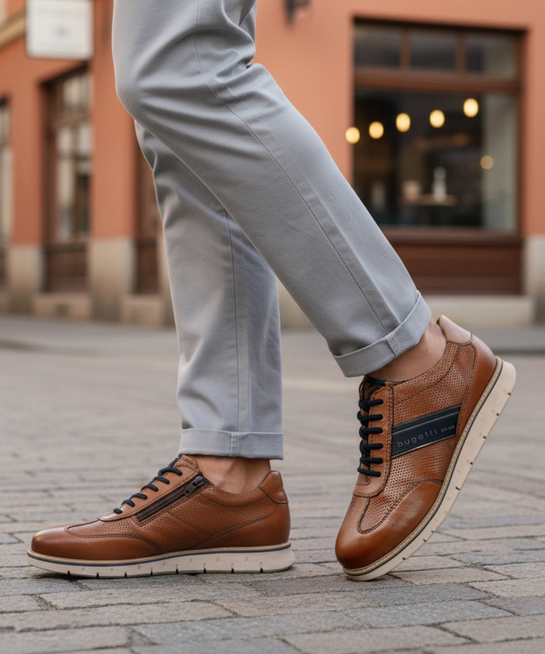 Lifestyle close-up of bugatti Sprinter cognac leather sneakers with black laces and zipper detail.