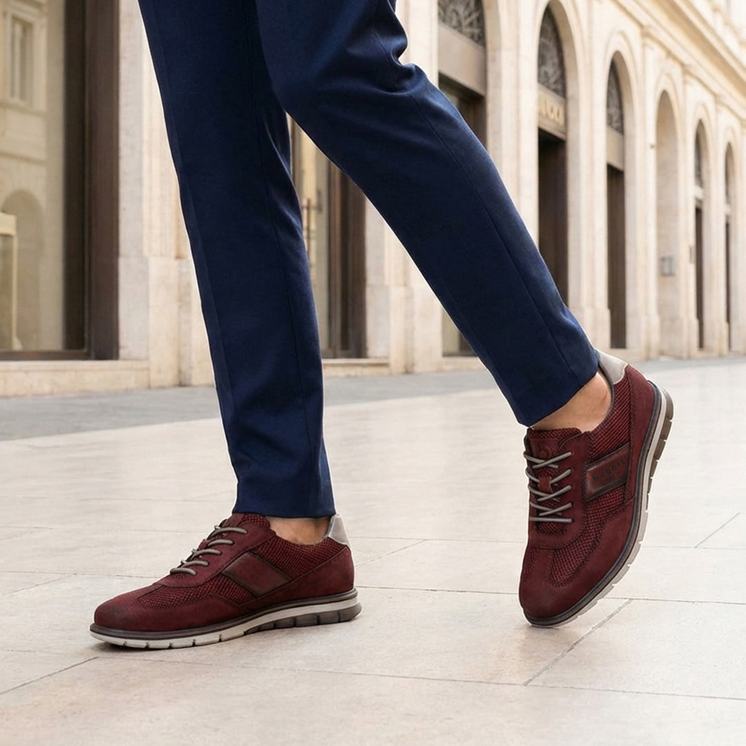 Cropped lifestyle image of bugatti Simone Comfort dark red leather casual shoes with grey soles, worn with blue trousers.
