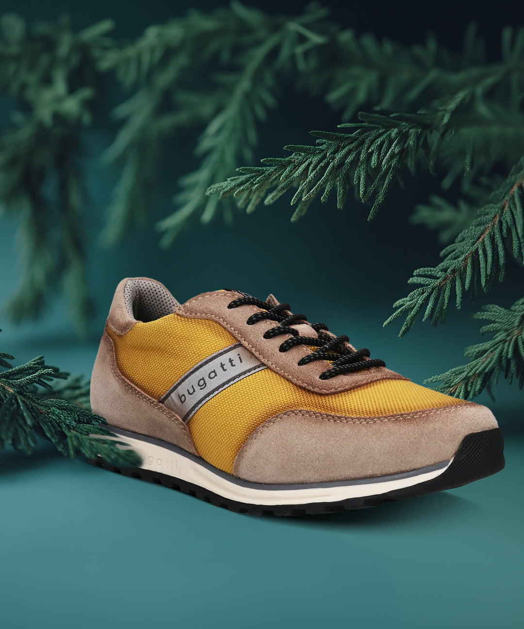 Taupe and yellow sneaker by bugatti, with black laces, styled with dark green conifer branches.
