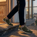 Lifestyle shot of bugatti Garnet Evo dark green leather sneakers with yellow and beige accents.
