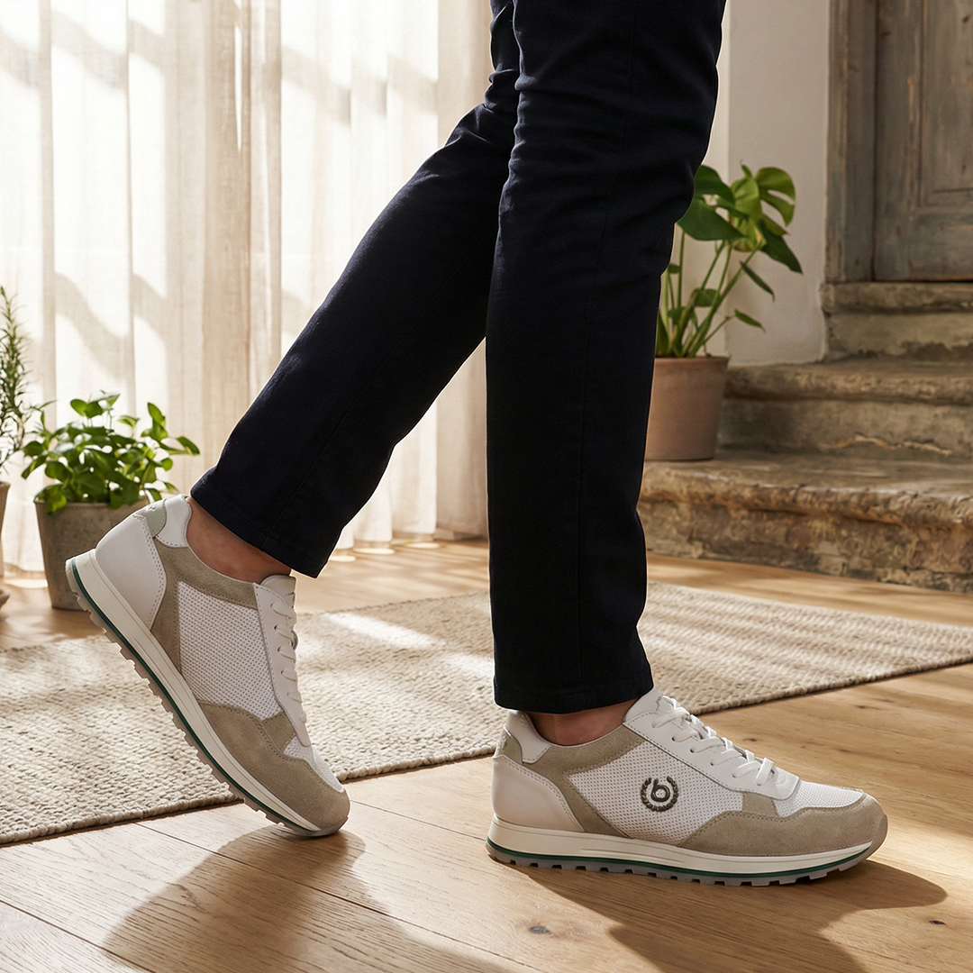Lifestyle shot of bugatti Garnet Evo Sand Premium Leather Comfort Sneakers, paired with dark trousers, and set on a wood floor.