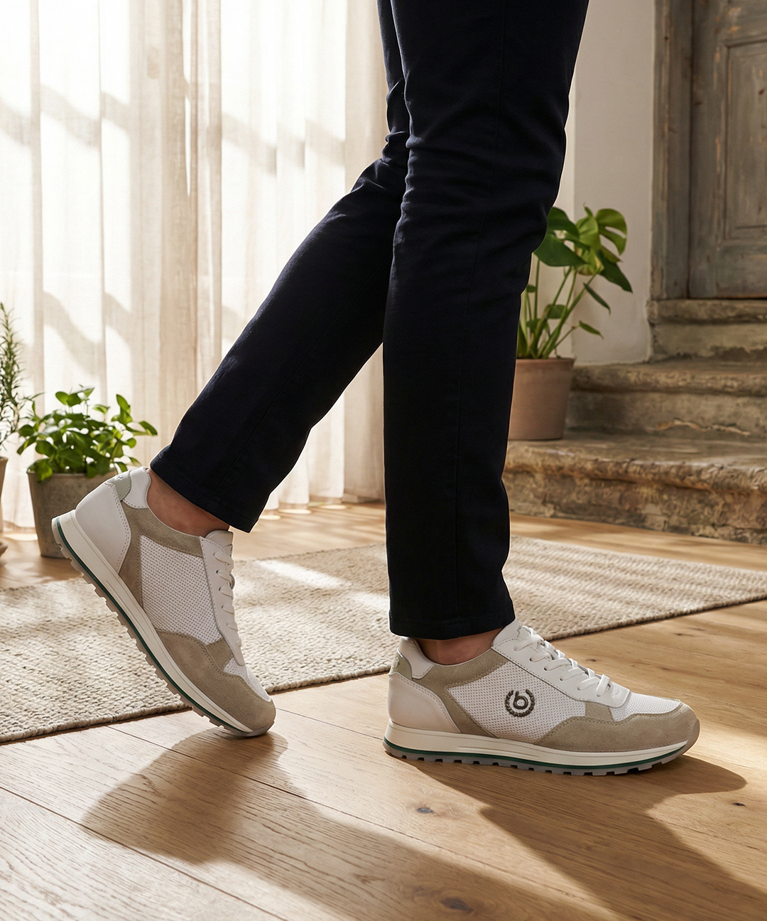 Lifestyle shot of bugatti Garnet Evo Sand Premium Leather Comfort Sneakers, paired with dark trousers, and set on a wood floor.