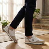 Lifestyle shot of bugatti Garnet Evo Sand Premium Leather Comfort Sneakers, paired with dark trousers, and set on a wood floor.