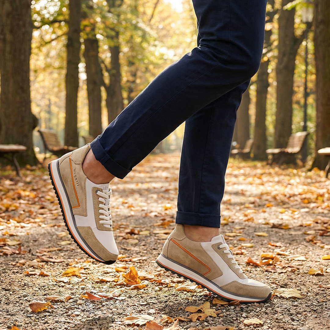 Lifestyle shot of bugatti Garnet Evo Sand sneakers in leather and suede, styled with navy trousers while walking on a path.