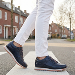 Lifestyle view of bugatti Garnet Evo dark blue leather sneakers with orange laces on a crosswalk.
