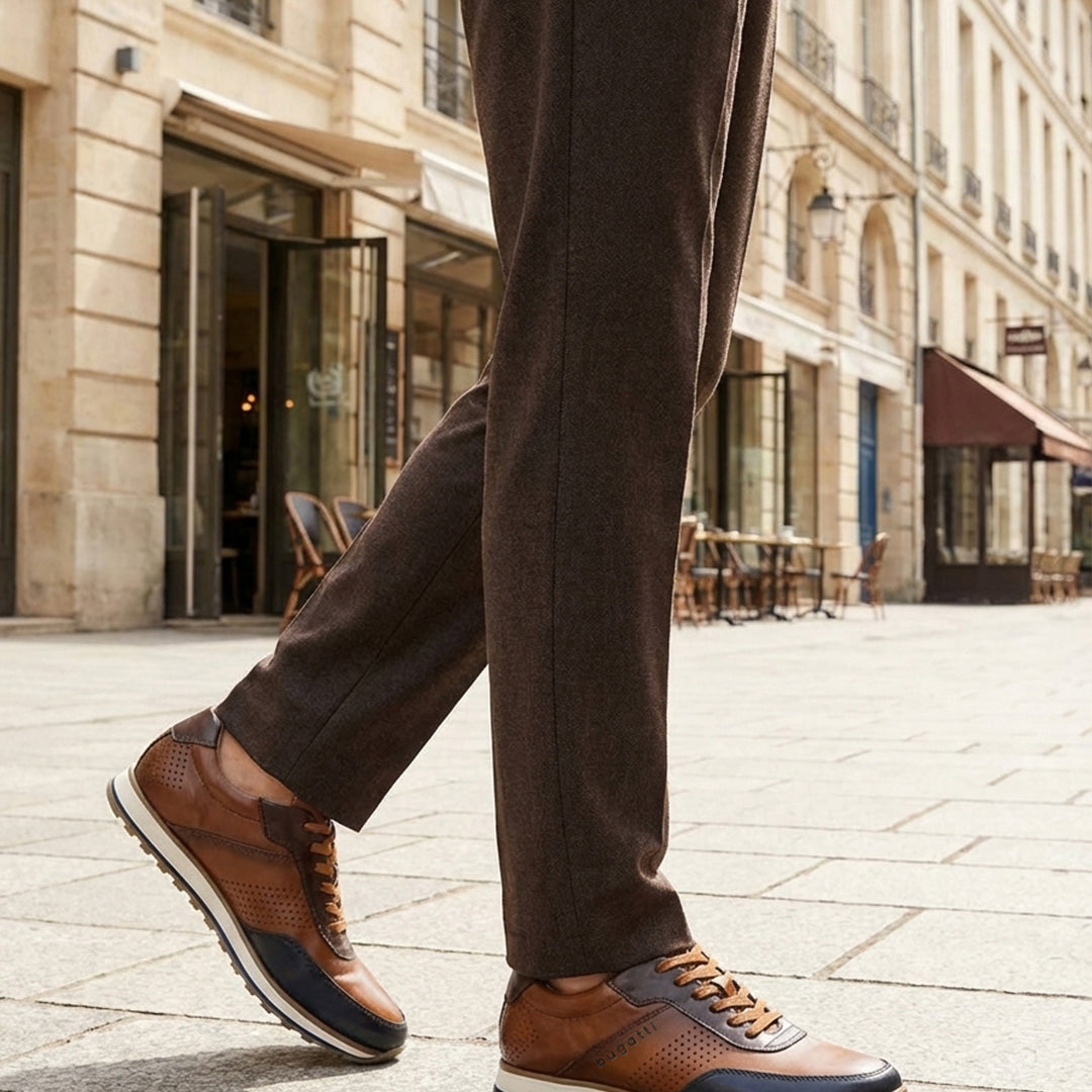 Lifestyle shot of bugatti Garnet Evo dark blue sneakers, with brown leather, perforated details, and a white sole. 
