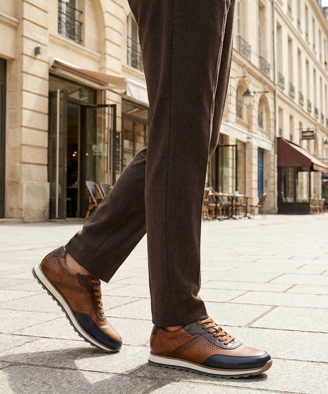 Lifestyle shot of bugatti Garnet Evo dark blue sneakers, with brown leather, perforated details, and a white sole. 
