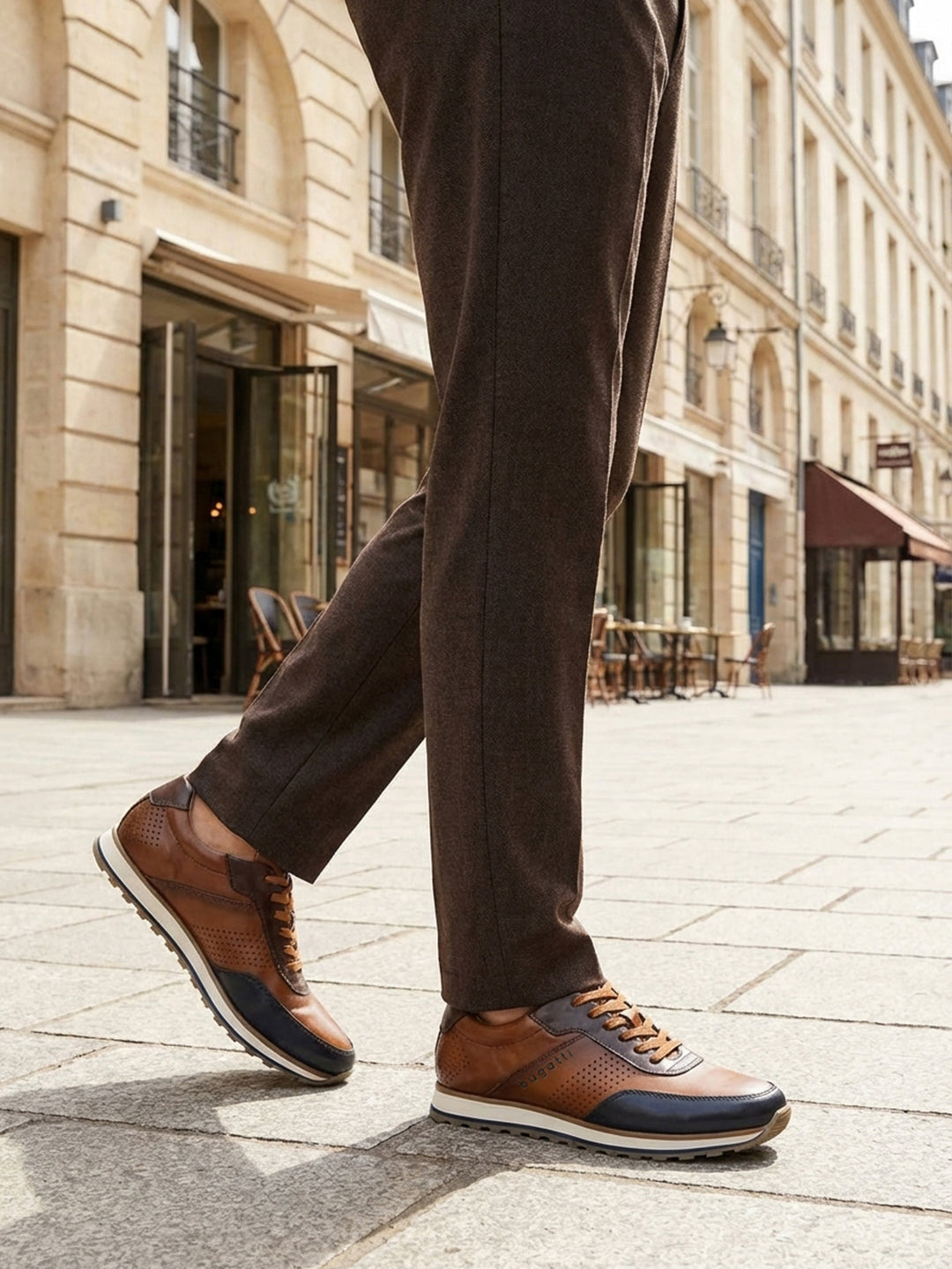 Lifestyle shot of bugatti Garnet Evo dark blue sneakers, with brown leather, perforated details, and a white sole. 
