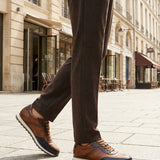 Lifestyle shot of bugatti Garnet Evo dark blue sneakers, with brown leather, perforated details, and a white sole. 
