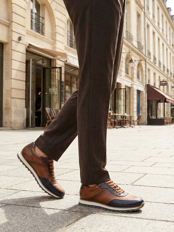 Lifestyle shot of bugatti Garnet Evo dark blue sneakers, with brown leather, perforated details, and a white sole. 
