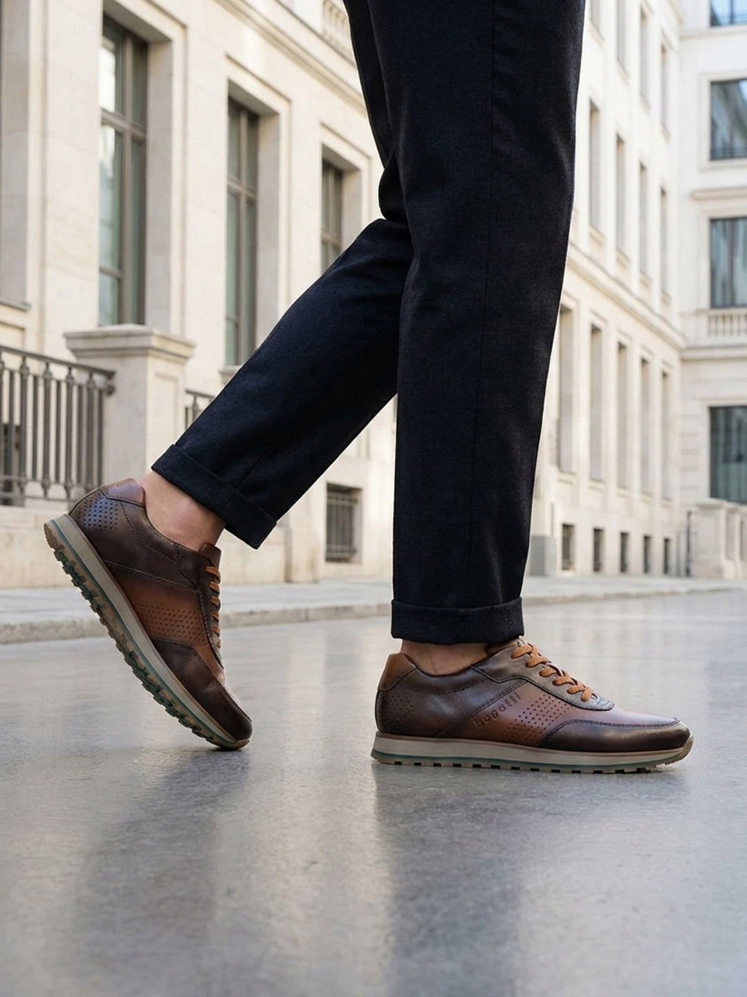 Lifestyle view of bugatti Garnet Evo dark brown premium leather sneakers with dark pants on a city street.
