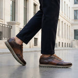 Lifestyle view of bugatti Garnet Evo dark brown premium leather sneakers with dark pants on a city street.