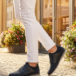 Lifestyle close-up of bugatti Sione Comfort dark blue casual shoes worn with white pants.
