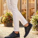 Lifestyle close-up of bugatti Sione Comfort dark blue casual shoes worn with white pants.
