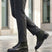 Lifestyle shot of bugatti Abel Black leather ankle boots with dark green textile detail, paired with gray dress pants.
