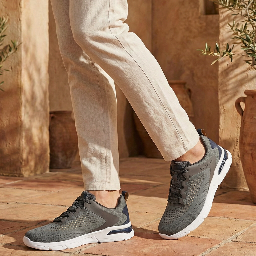 Lifestyle shot of bugatti Nubola dark gray sneakers with a white sole, paired with khaki-colored pants.
