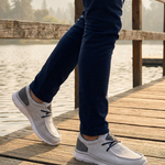 Lifestyle image of bugatti Soa light gray comfort mid-top sneakers with a gray heel patch, worn with navy pants.
