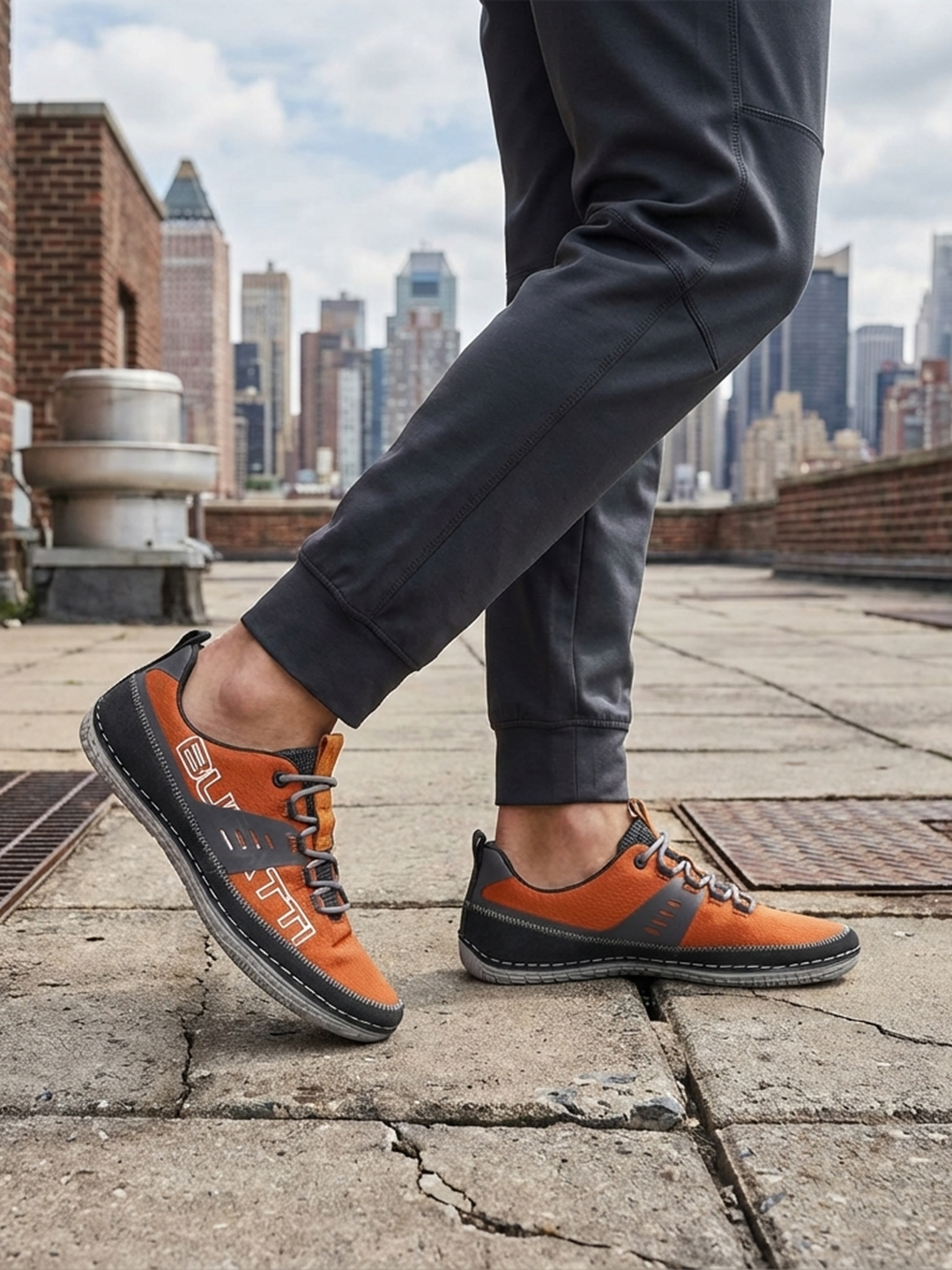 Lifestyle image of bugatti Bimini orange comfort low top sneakers with gray trim and gray laces.

