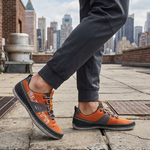 Lifestyle image of bugatti Bimini orange comfort low top sneakers with gray trim and gray laces.
