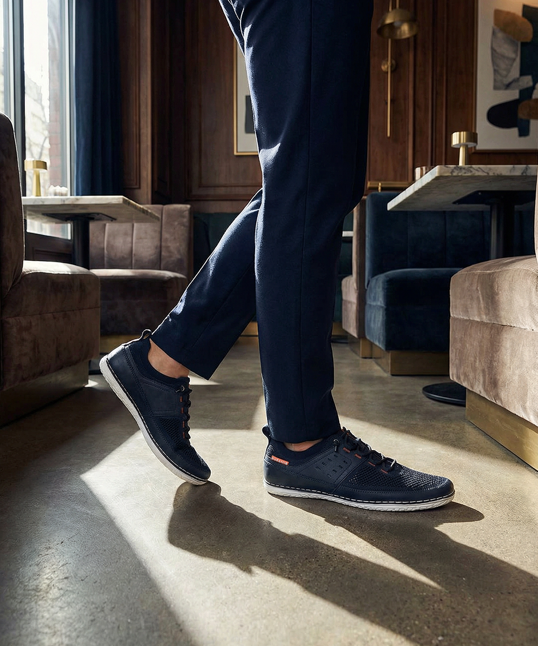 Lifestyle shot of bugatti Bimini dark blue low top sneakers with white soles, paired with blue trousers.
