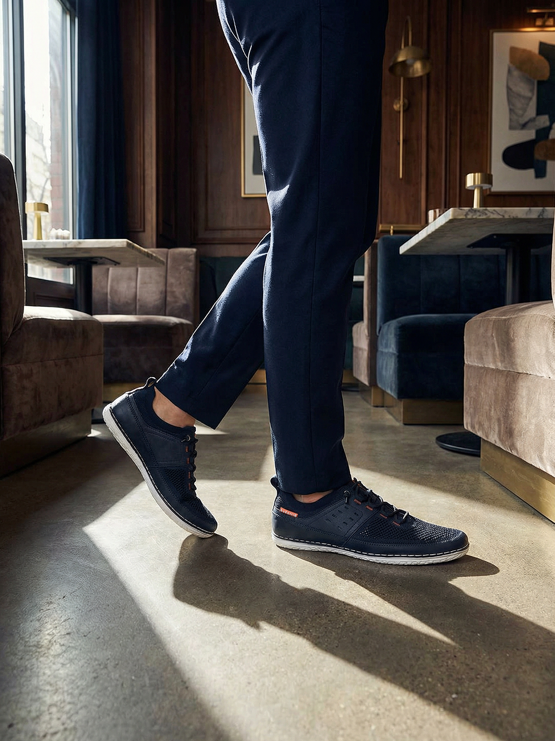 Lifestyle shot of bugatti Bimini dark blue low top sneakers with white soles, paired with blue trousers.
