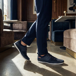 Lifestyle shot of bugatti Bimini dark blue low top sneakers with white soles, paired with blue trousers.
