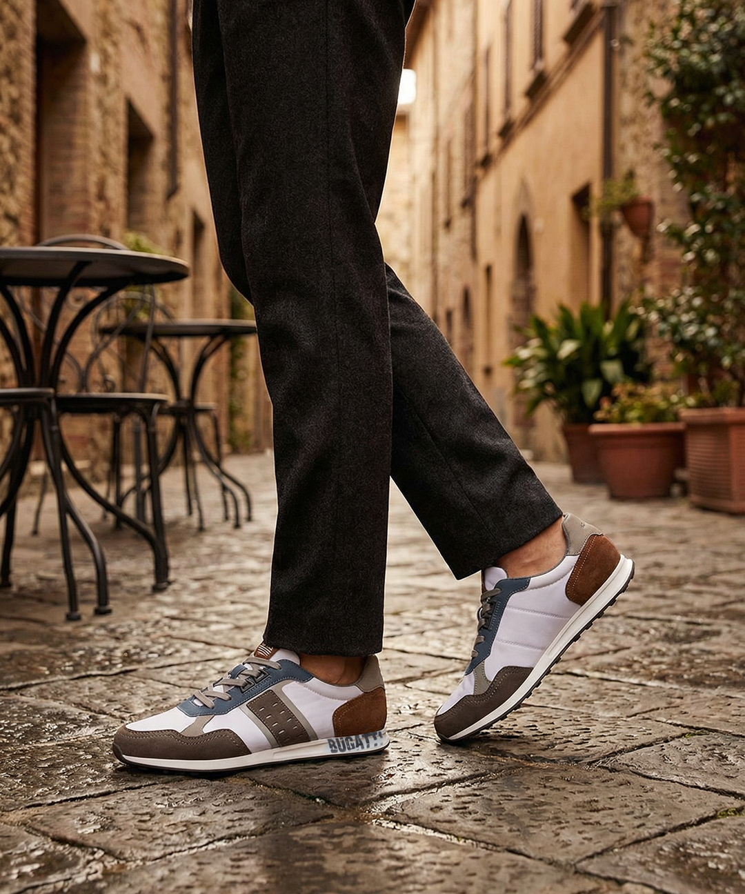 Lifestyle view of bugatti Ross multicoloured sneakers with grey and brown accents, styled with black trousers.