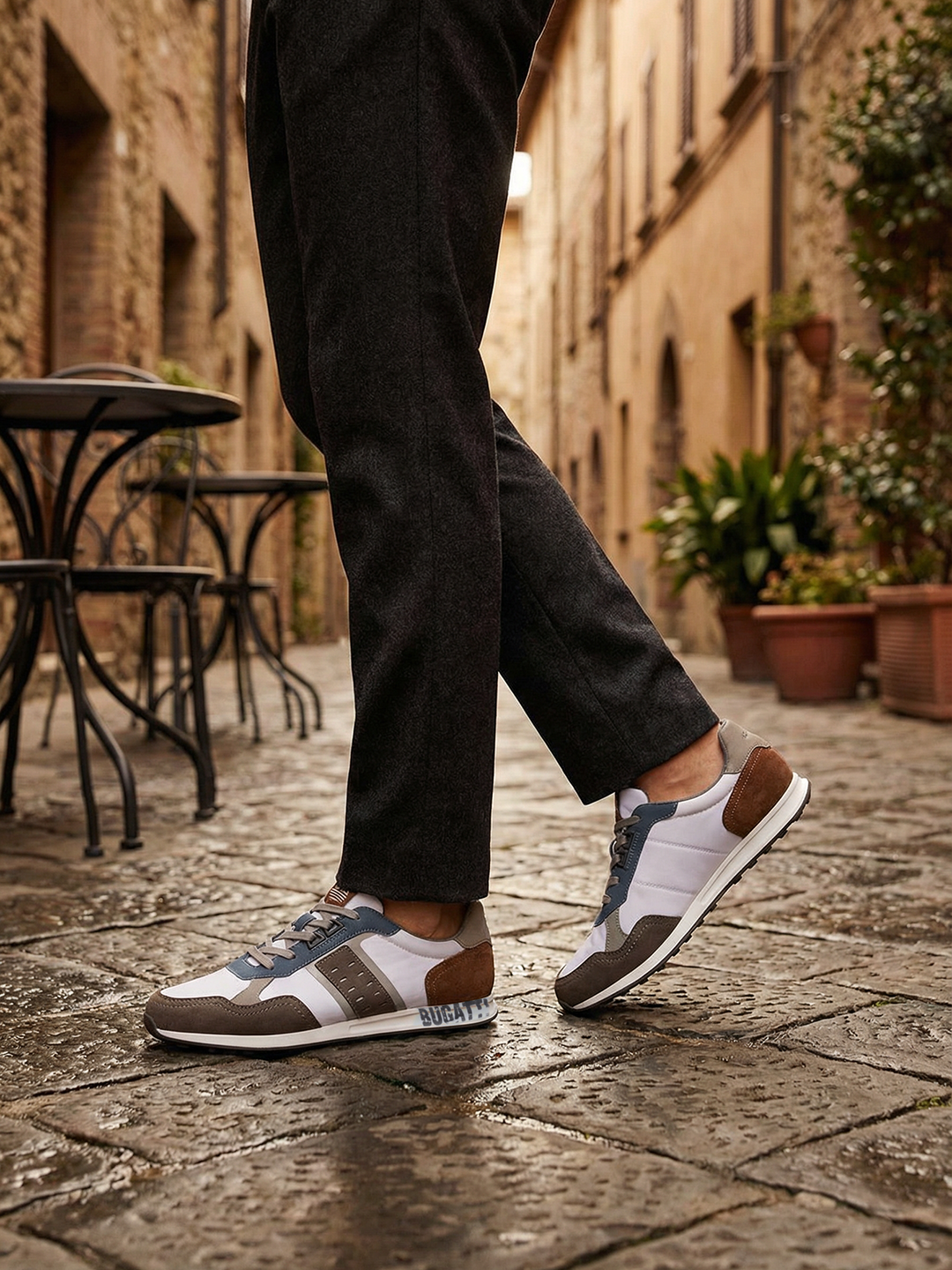 Lifestyle view of bugatti Ross multicoloured sneakers with grey and brown accents, styled with black trousers.