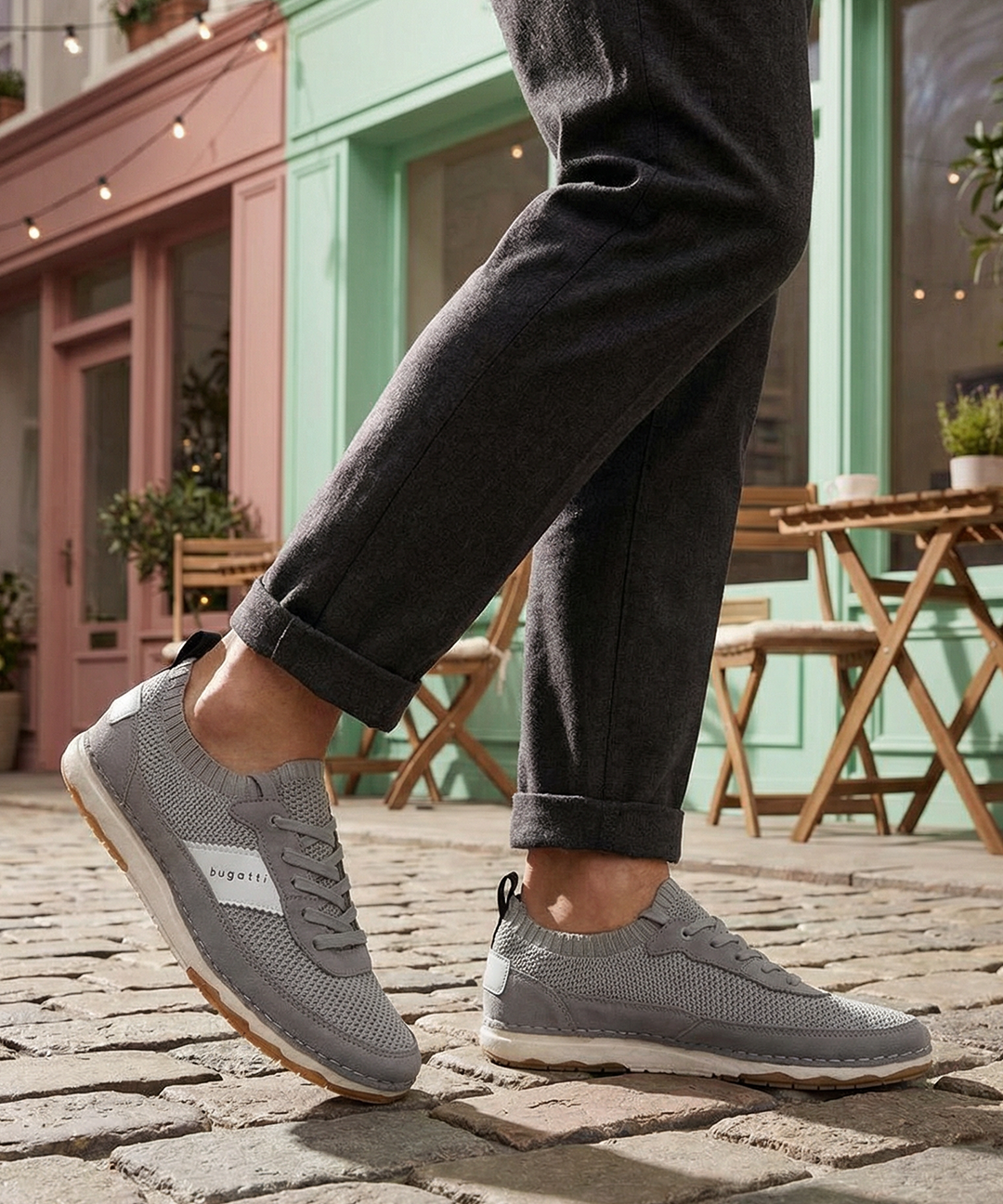 Grey low top sneakers by bugatti with a knit texture and white accent stripes, worn with dark grey pants.