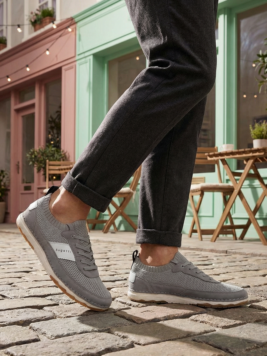 Lifestyle close-up of bugatti Vanadium Grey Comfort Low Top Sneakers worn with grey pants and on a cobblestone street.
