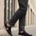 Lifestyle shot of bugatti Romer black canvas sneakers with beige soles, styled with gray dress pants.
