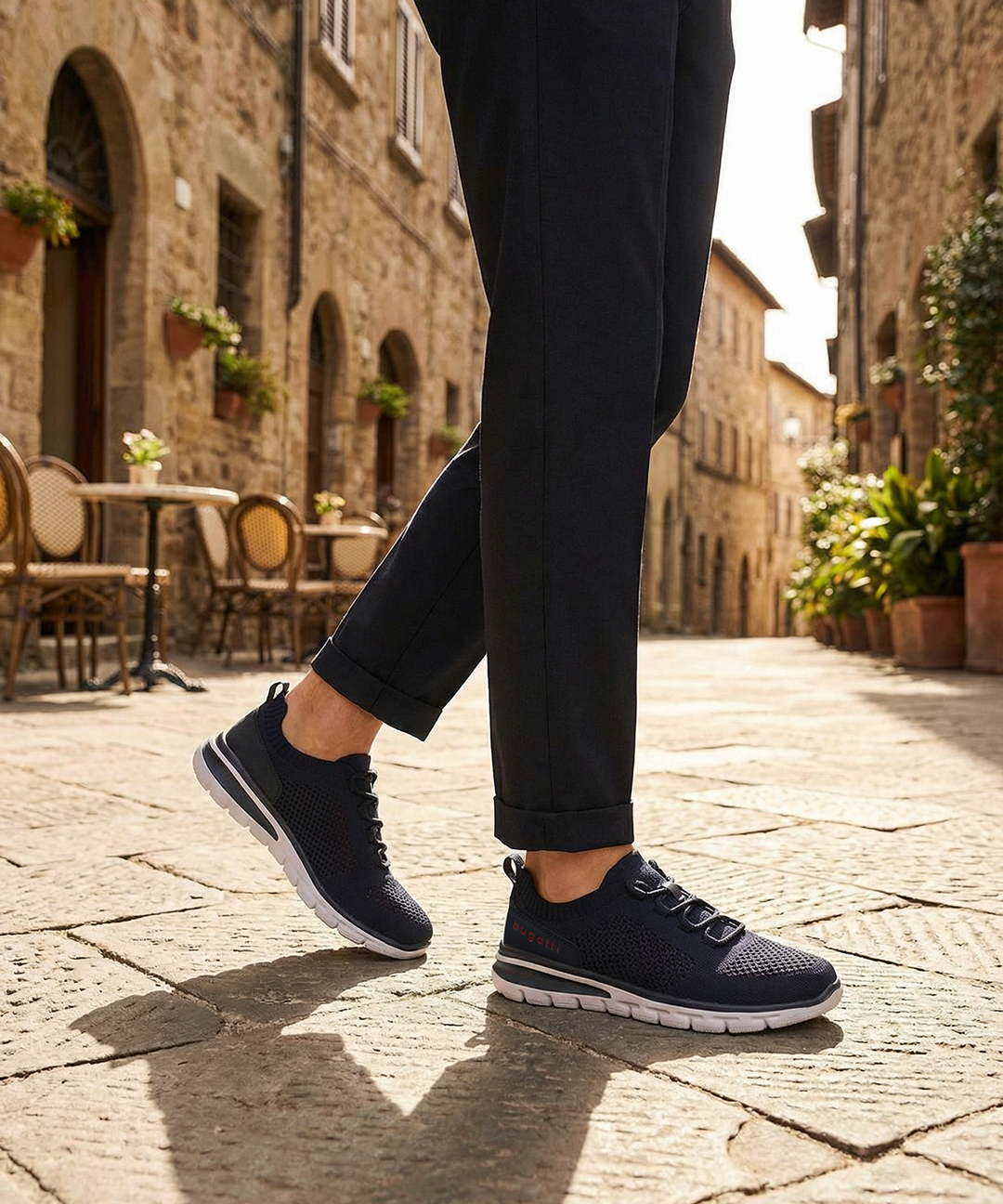 Lifestyle image of bugatti Yucatan dark blue comfort sneakers with a white sole and knitted texture, paired with dark pants.