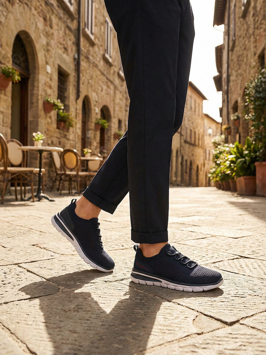 Lifestyle image of bugatti Yucatan dark blue comfort sneakers with a white sole and knitted texture, paired with dark pants.