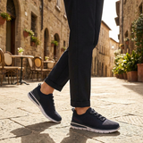 Lifestyle image of bugatti Yucatan dark blue comfort sneakers with a white sole and knitted texture, paired with dark pants.