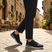 Lifestyle image of bugatti Yucatan dark blue comfort sneakers with a white sole and knitted texture, paired with dark pants.