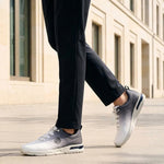 Cropped lifestyle view of bugatti Nubola white athleisure sneakers with a gradient design and white soles, worn with black trousers.
