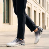 Cropped lifestyle view of bugatti Nubola white athleisure sneakers with a gradient design and white soles, worn with black trousers.
