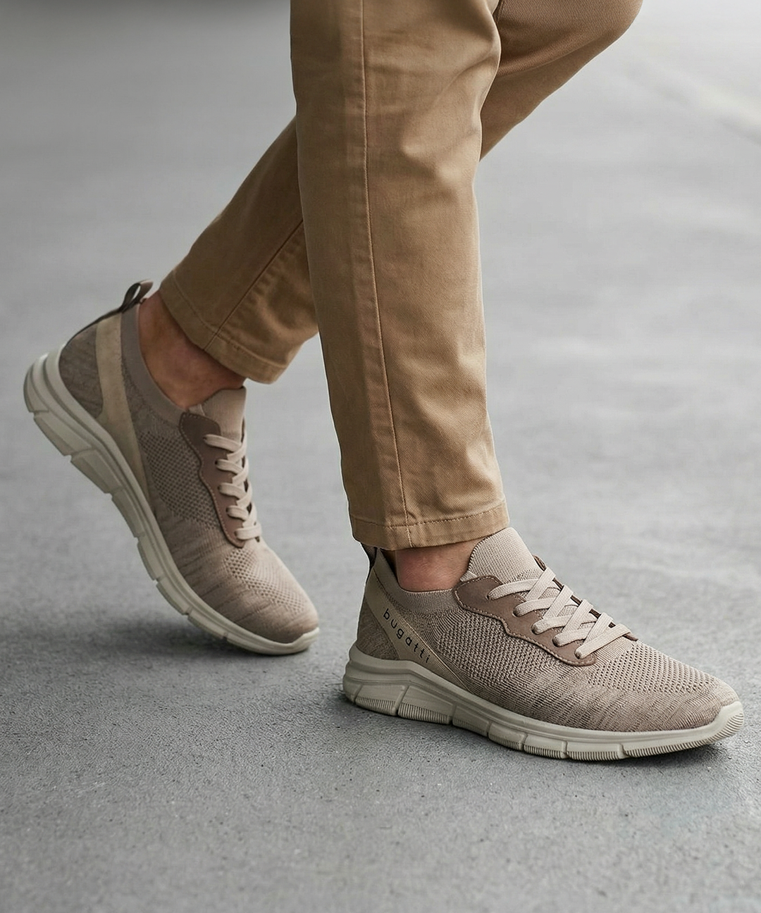 Lifestyle shot of bugatti Soa beige sneakers; a woven knit upper with matching khaki casual pants.
