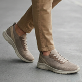 Lifestyle shot of bugatti Soa beige sneakers; a woven knit upper with matching khaki casual pants.
